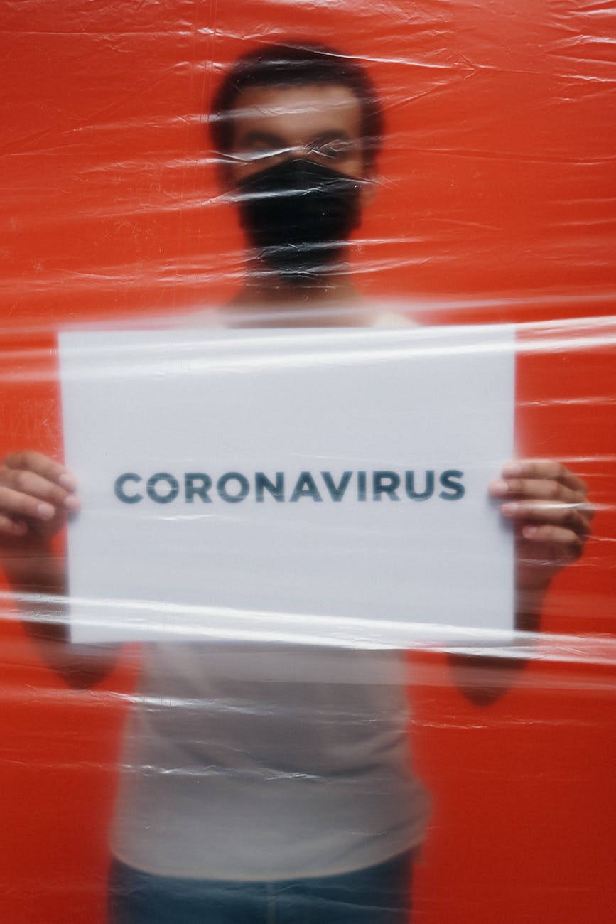 man in isolation holding a placard with coronavirus text